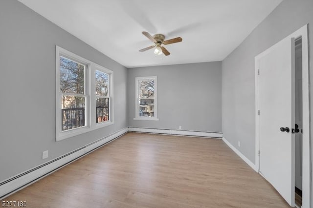 empty room with a baseboard radiator, light hardwood / wood-style flooring, and plenty of natural light