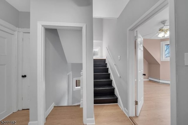 stairway featuring wood-type flooring, ceiling fan, and a baseboard heating unit