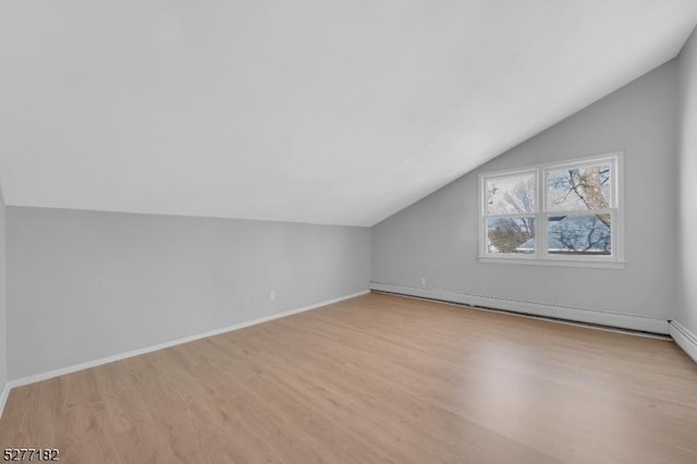 additional living space featuring light hardwood / wood-style flooring, baseboard heating, and lofted ceiling