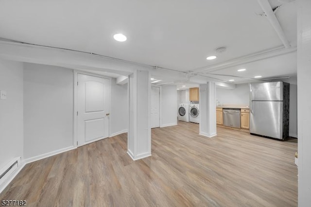 basement featuring washer and dryer, light wood-type flooring, stainless steel refrigerator, and a baseboard heating unit