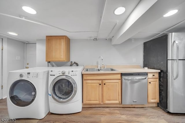 laundry room with separate washer and dryer, light hardwood / wood-style floors, and sink