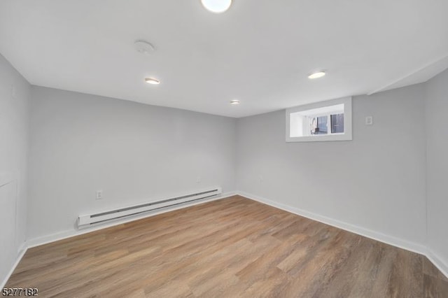 empty room with baseboard heating and light hardwood / wood-style flooring