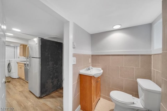 bathroom featuring hardwood / wood-style floors, vanity, toilet, and tile walls