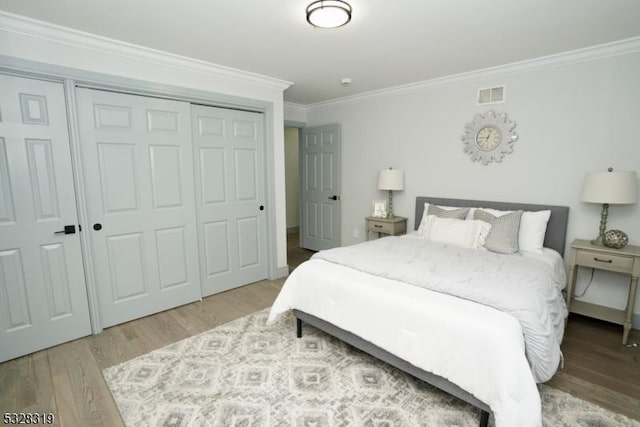 bedroom with a closet, light hardwood / wood-style floors, and ornamental molding