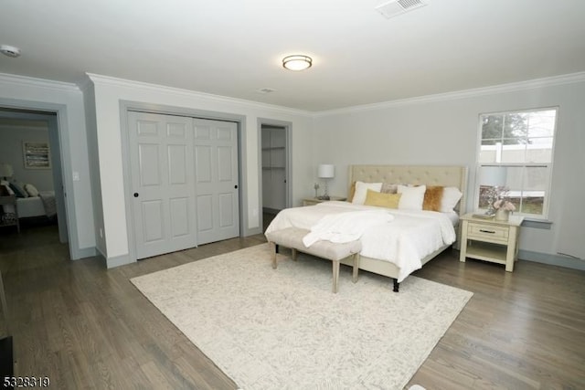 bedroom featuring dark hardwood / wood-style floors, ornamental molding, and a closet