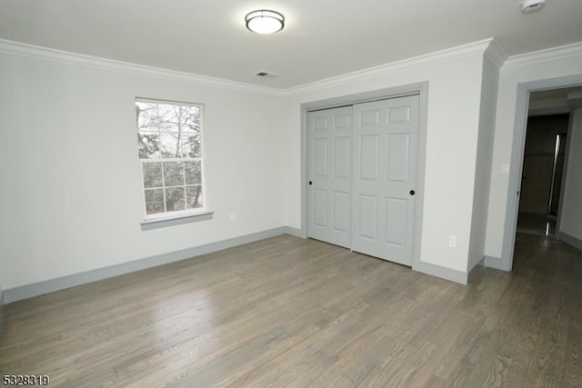 unfurnished bedroom with hardwood / wood-style flooring, a closet, and ornamental molding