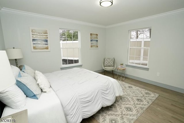 bedroom featuring hardwood / wood-style floors, ornamental molding, and multiple windows