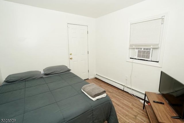 bedroom featuring wood-type flooring and a baseboard heating unit