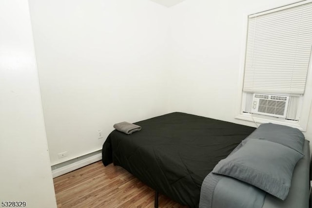 bedroom featuring baseboard heating, cooling unit, and wood-type flooring