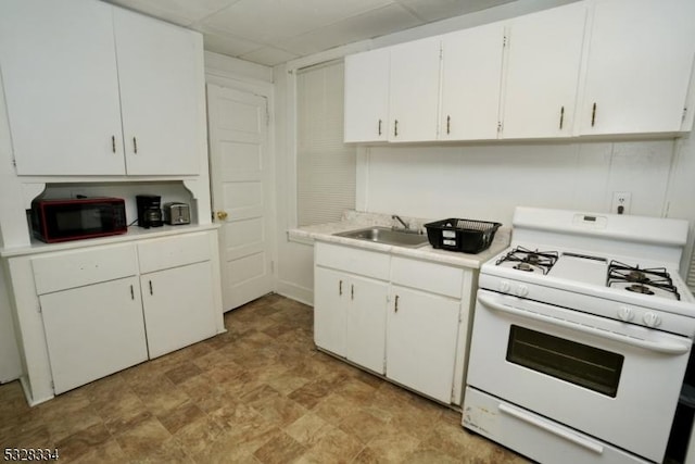 kitchen with white gas range oven, white cabinetry, and sink