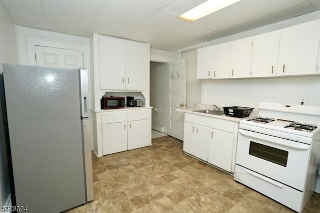 kitchen featuring white cabinets, white stove, fridge, and sink