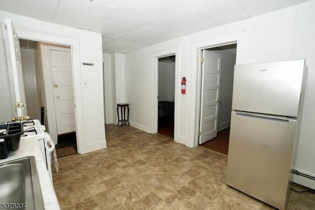 kitchen featuring a paneled ceiling, white fridge, sink, and a baseboard radiator