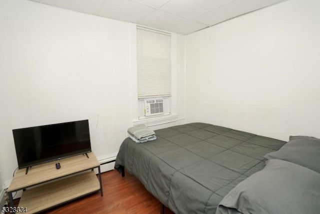 bedroom featuring cooling unit, baseboard heating, and dark wood-type flooring