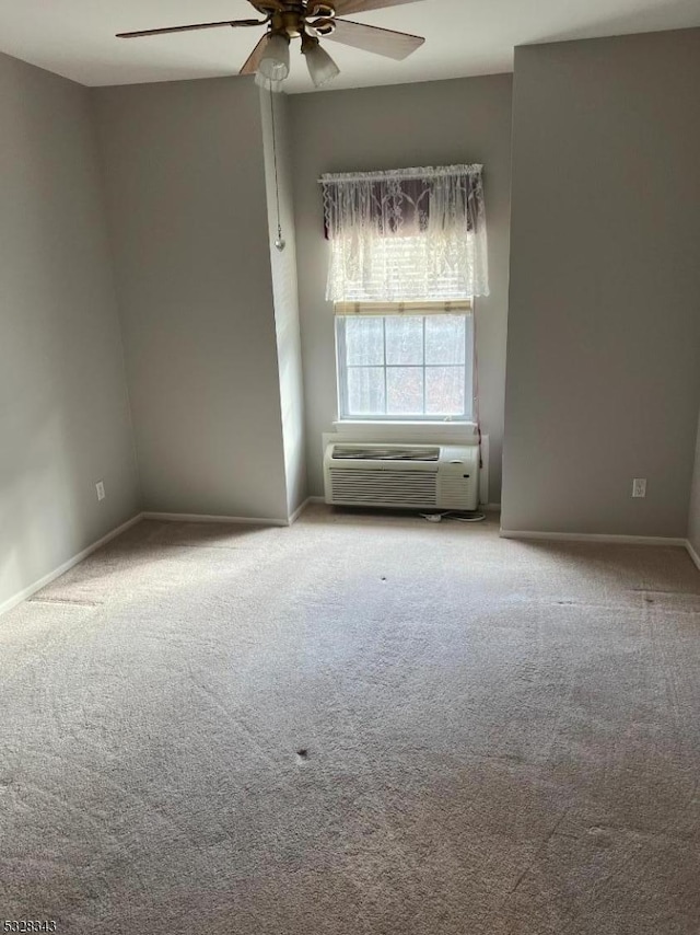 unfurnished room featuring an AC wall unit, ceiling fan, carpet, and baseboards
