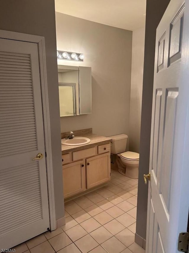 half bathroom featuring toilet, tile patterned floors, and vanity
