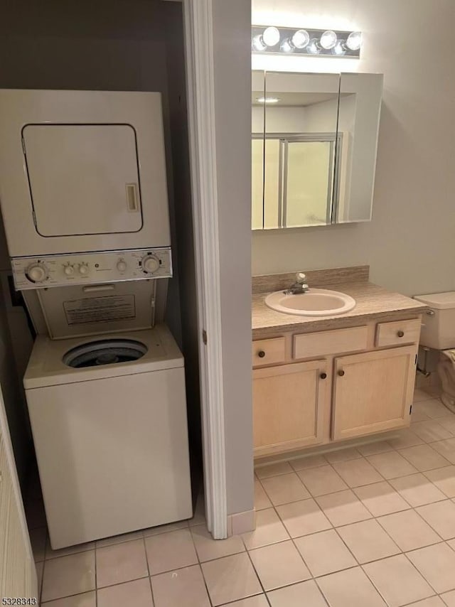 bathroom with toilet, stacked washer and dryer, vanity, and tile patterned flooring