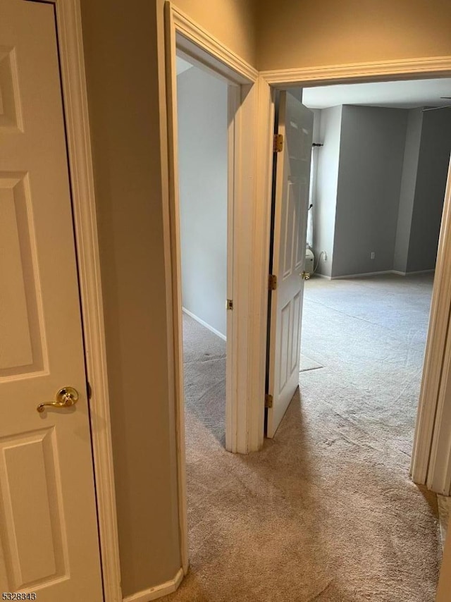 corridor featuring baseboards and carpet