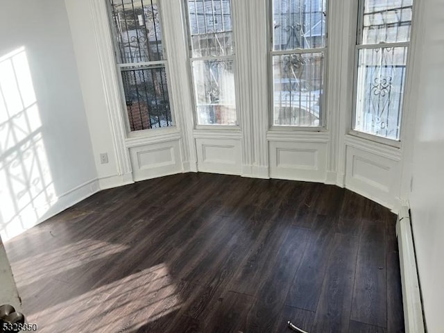 unfurnished dining area with dark hardwood / wood-style floors and a baseboard heating unit