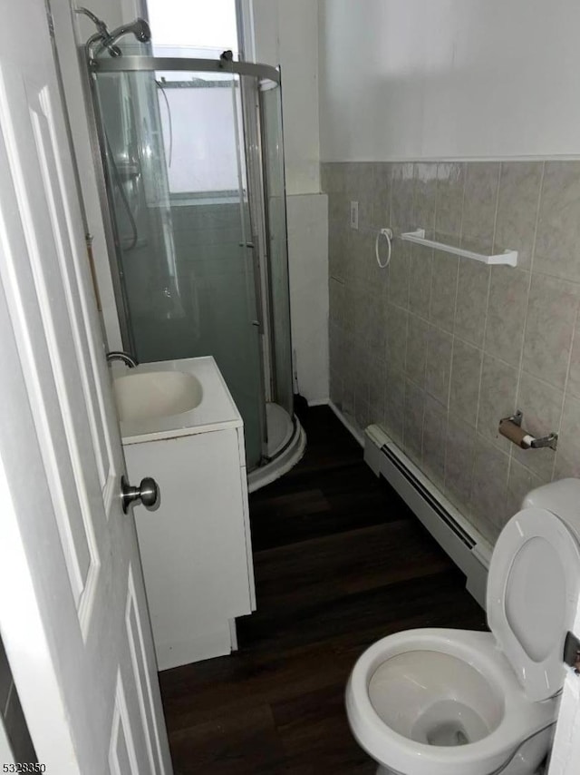 bathroom with vanity, hardwood / wood-style flooring, tile walls, toilet, and a shower with shower door