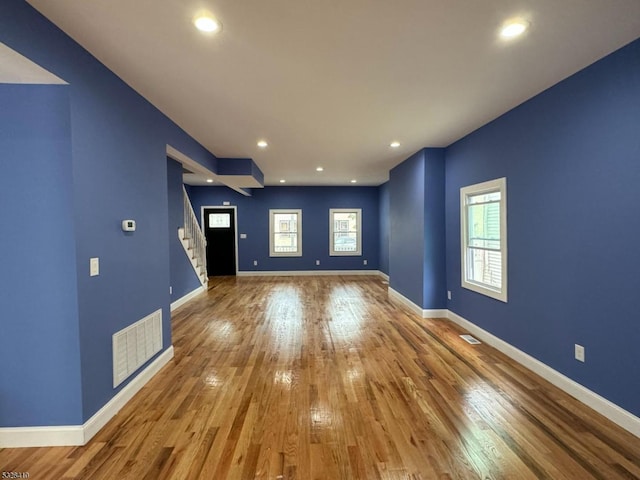 unfurnished living room featuring a wealth of natural light and hardwood / wood-style flooring