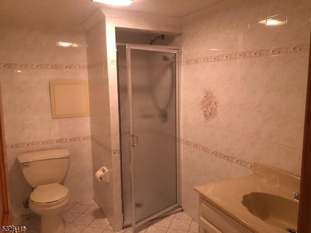 bathroom with tile patterned flooring, vanity, an enclosed shower, and tile walls