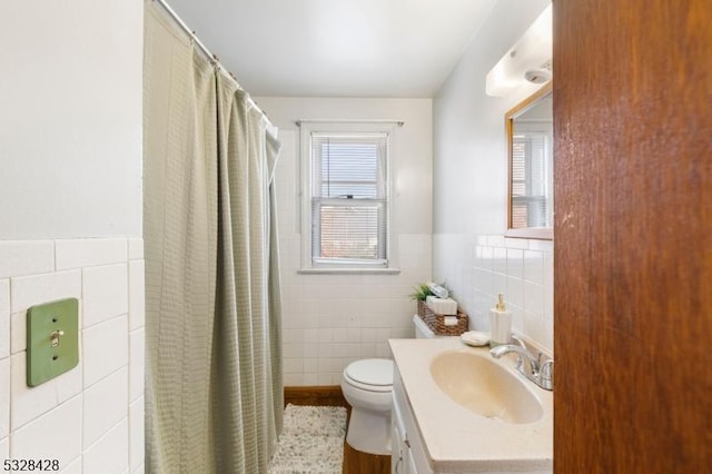 bathroom with vanity, toilet, tile walls, and walk in shower