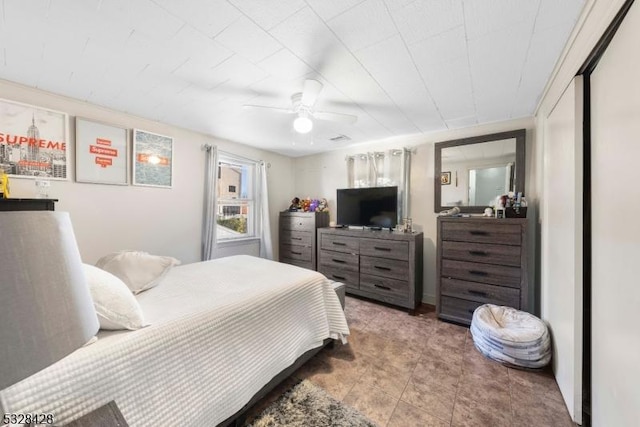 tiled bedroom featuring ceiling fan and a closet