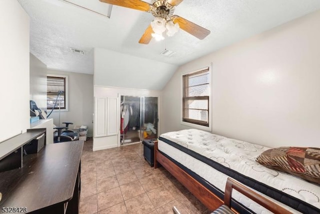 bedroom with vaulted ceiling, ceiling fan, light tile patterned floors, a textured ceiling, and a closet