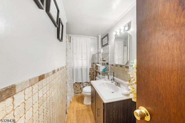 bathroom with vanity, crown molding, hardwood / wood-style flooring, tile walls, and toilet