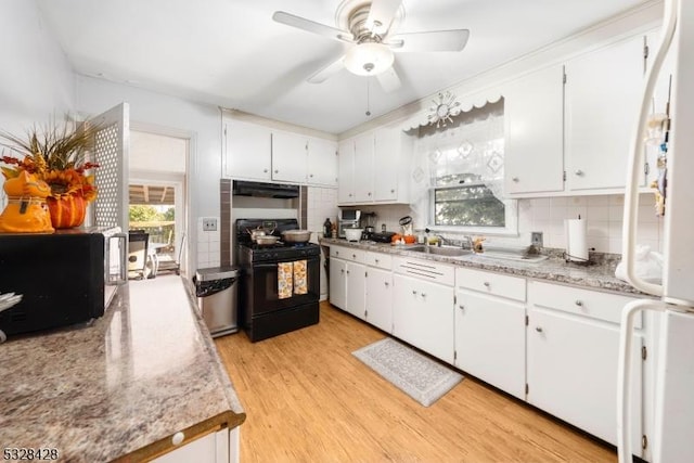 kitchen with white cabinetry, black range with gas stovetop, backsplash, white fridge, and light wood-type flooring