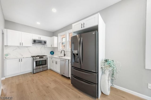 kitchen featuring appliances with stainless steel finishes, light wood-type flooring, white cabinetry, and sink