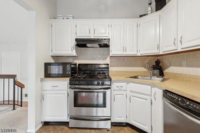 kitchen featuring white cabinetry, sink, stainless steel appliances, tasteful backsplash, and dark tile patterned floors