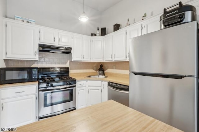 kitchen with decorative backsplash, stainless steel appliances, sink, white cabinets, and hanging light fixtures