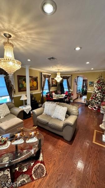 living room with hardwood / wood-style floors, ornamental molding, and an inviting chandelier