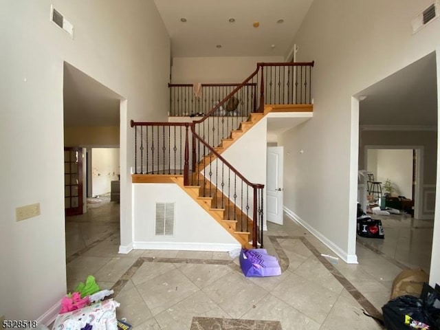 stairs featuring a high ceiling and ornamental molding