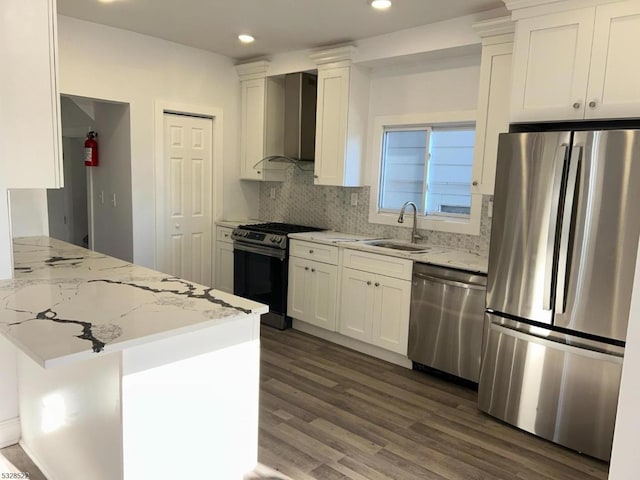 kitchen with appliances with stainless steel finishes, dark hardwood / wood-style flooring, wall chimney exhaust hood, sink, and white cabinetry