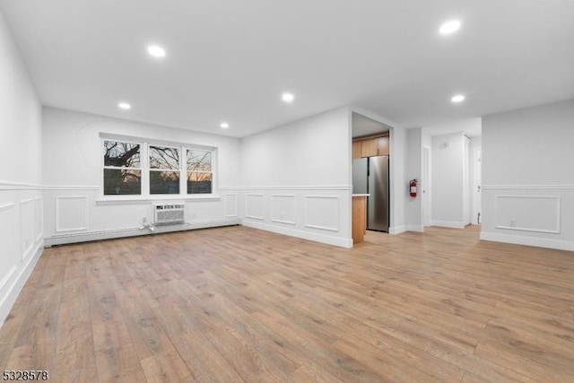 unfurnished living room featuring a wall mounted air conditioner and light wood-type flooring