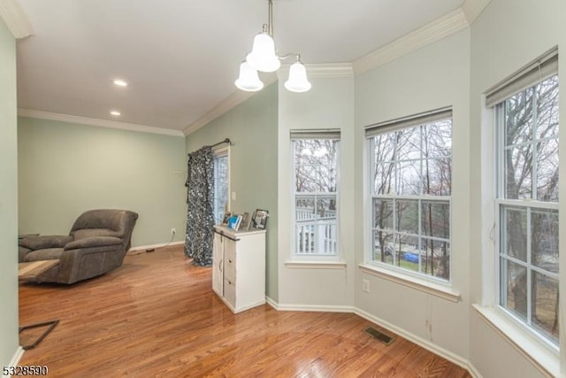 interior space with light hardwood / wood-style floors, an inviting chandelier, and ornamental molding