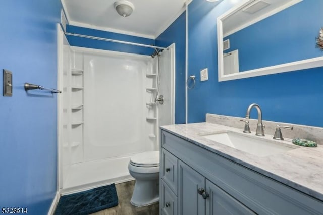 bathroom with vanity, a shower, hardwood / wood-style flooring, toilet, and ornamental molding