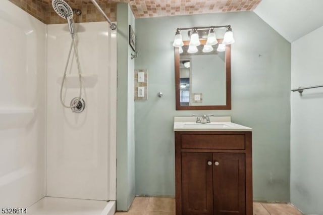 bathroom with a shower, tile patterned flooring, vanity, and vaulted ceiling