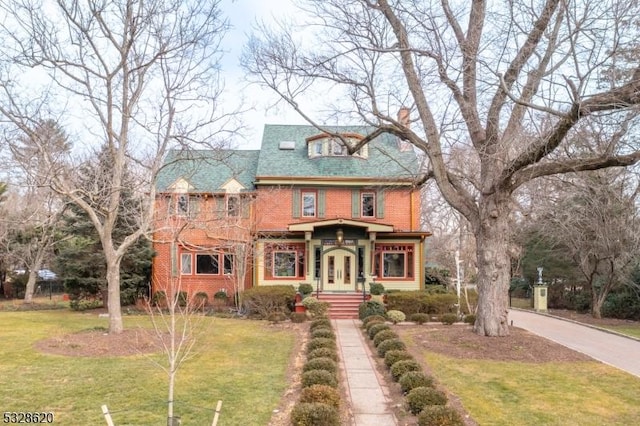 view of front of house with a front lawn, a chimney, and brick siding