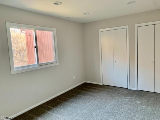 unfurnished bedroom with multiple closets and carpet floors