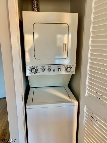 laundry room featuring stacked washer and dryer and wood-type flooring