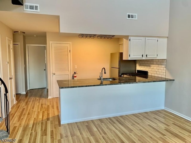 kitchen featuring white cabinets, light hardwood / wood-style floors, kitchen peninsula, and sink