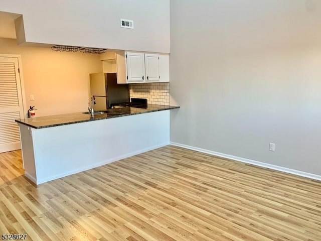 kitchen featuring white cabinetry, light wood-type flooring, kitchen peninsula, and stainless steel refrigerator