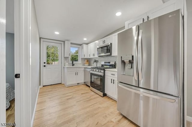 kitchen featuring light hardwood / wood-style floors, white cabinetry, stainless steel appliances, and tasteful backsplash