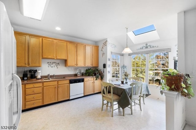 kitchen with vaulted ceiling with skylight, decorative light fixtures, white appliances, and sink