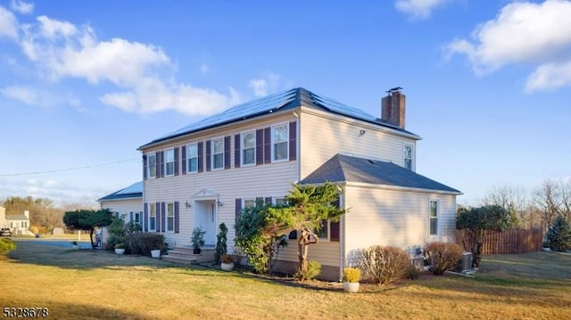 view of front of property featuring a front lawn and solar panels