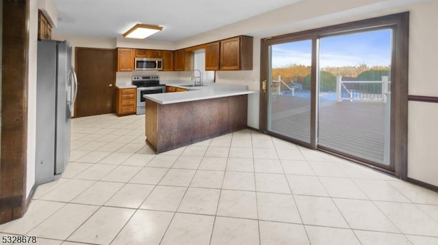 kitchen with kitchen peninsula, sink, light tile patterned floors, and appliances with stainless steel finishes