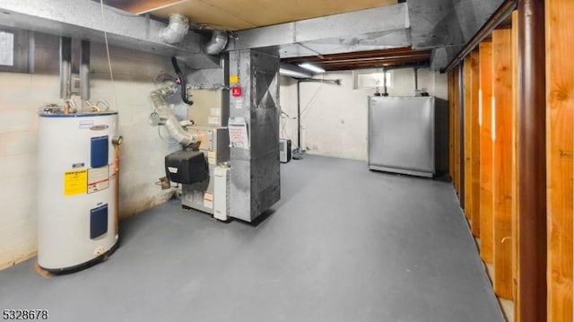 basement with heating unit, stainless steel refrigerator, and water heater